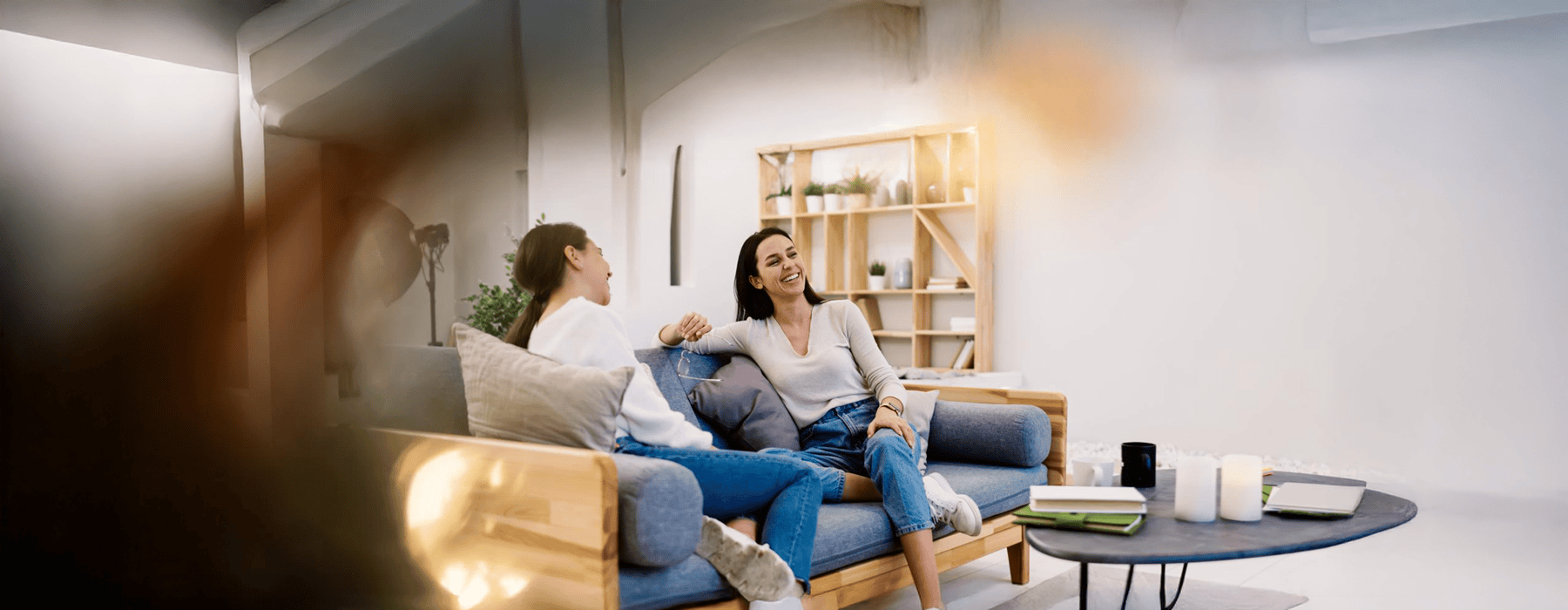 a person sitting on a couch with another woman sitting on the couch
